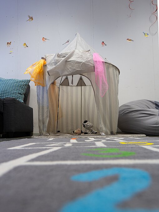 Ein Spielzelt, das liebevoll geschmückt ist, steht in einem Raum
