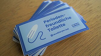 Ein Stapel Sticker mit der Aufschrift Periodenfreundliche Toilette