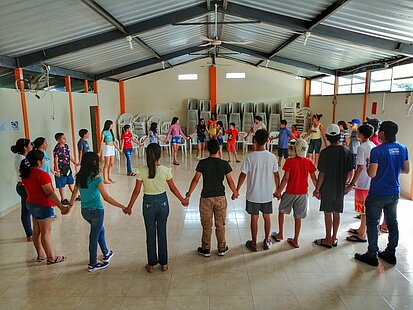Viele Kinder halten sich in einem Kreis stehend an den Händen