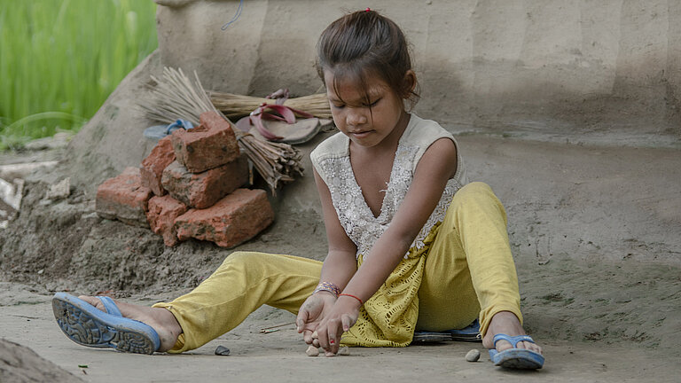 Bhumika spielt mit Steinen auf dem Boden.
