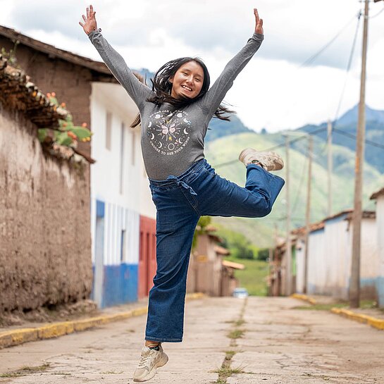 Eine junge Frau springt auf einem Bein in die Luft