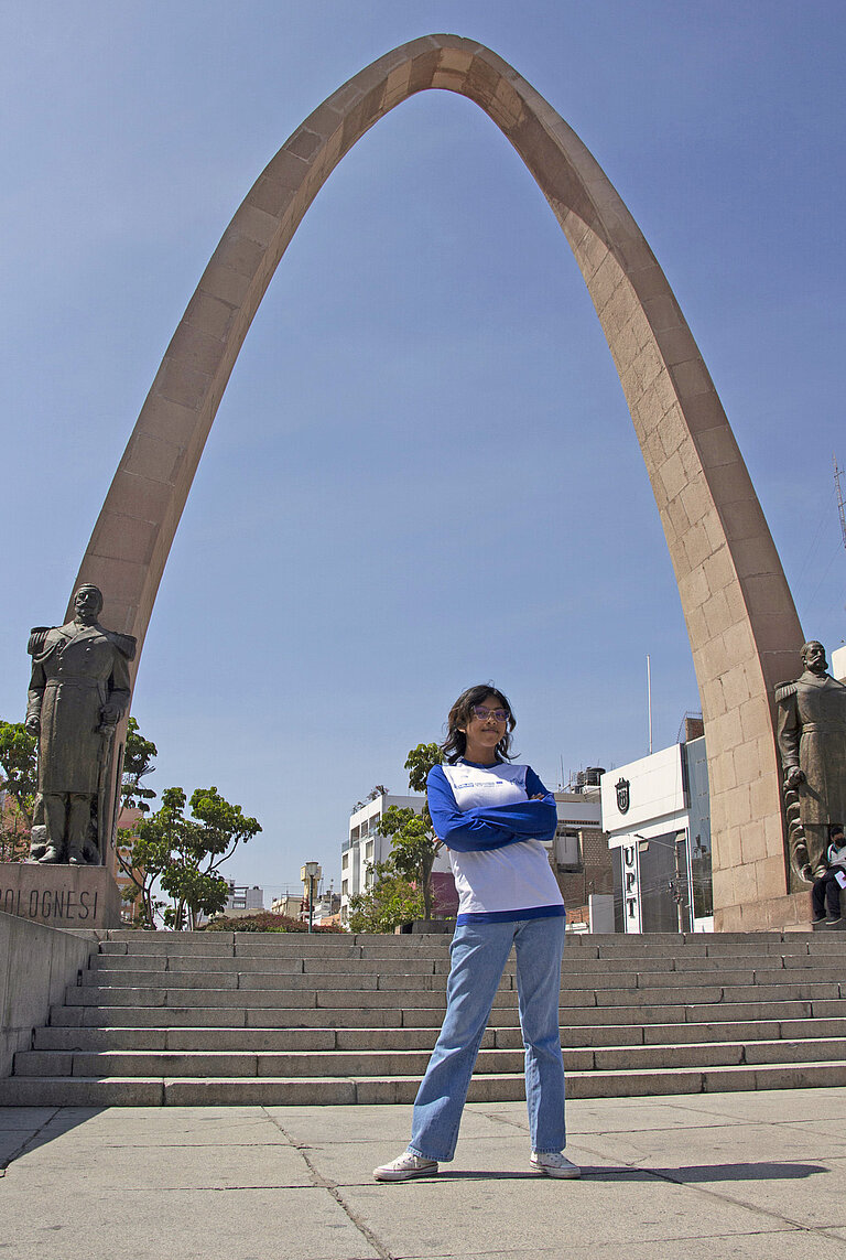 Ein Mädchen steht vor einem Monument in Peru