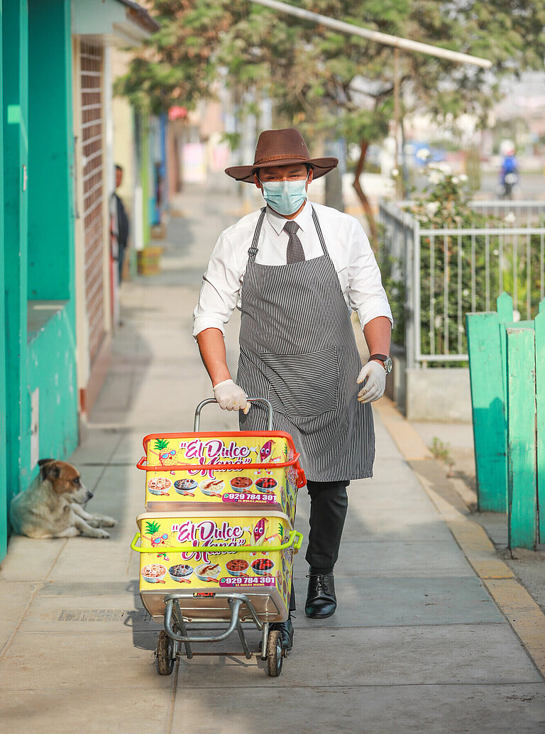 Ein Mann rollt einen Karren mit Süßspeisen durch eine Straße