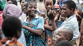Mädchen und Frauen tanzen und lachen bei einer Gemeinschaftsveranstaltung in Malawi