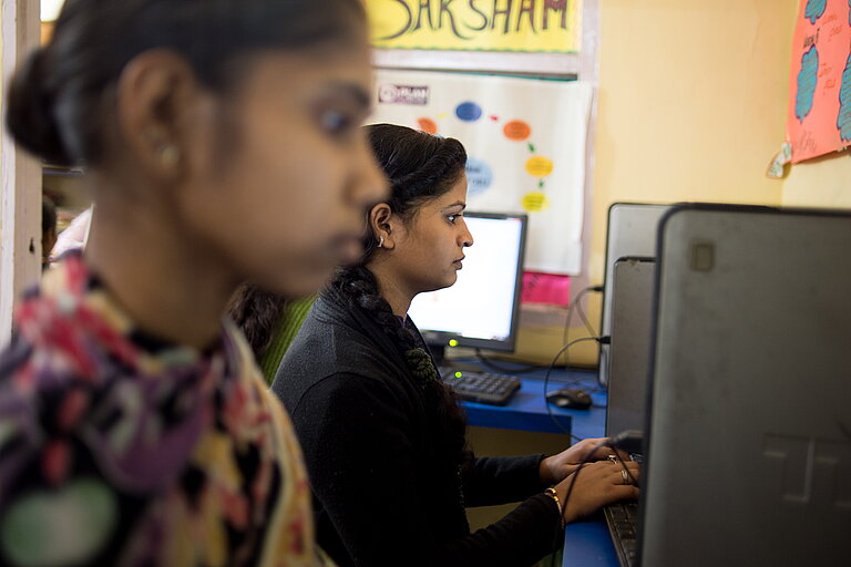 Zwei junge Frauen sitzen vor Computern.