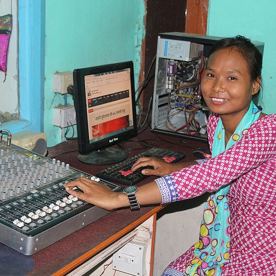 Junge Frau in Nepal arbeitet als Tontechnikerin an einem Mischpult in einem Radiosender