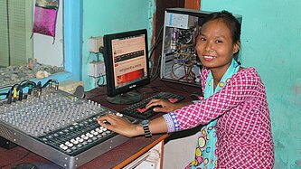 Junge Frau in Nepal arbeitet als Tontechnikerin an einem Mischpult in einem Radiosender