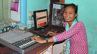 Junge Frau in Nepal arbeitet als Tontechnikerin an einem Mischpult in einem Radiosender