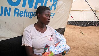 Die 19jährige Renatha sitzt mit ihrem Baby vor ihrem Zelt im Mahama Camp © Plan