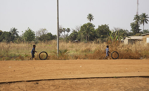 Zwei Kinder spielen mit Reifen auf einem Feld.