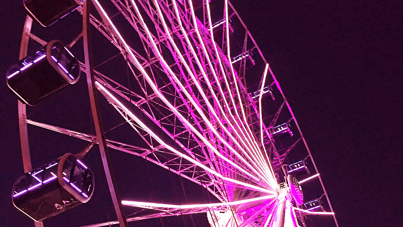 Ein Ausschnitt des Riesenrads in München, in pink angestrahlt.