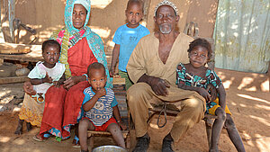 Großeltern mit Enkelkindern vor ihrem Zuhause in einem afrikanischen Dorf
