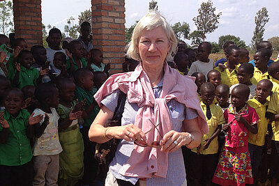 Sabine Sieb auf Projektreise in Ruanda, umgeben von Kindern in Schuluniformen