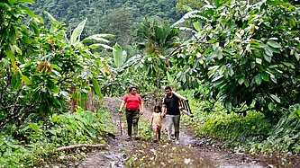 Yenny steht gemeinsam mit ihrem Mann und ihrer jüngsten Tochter in einer ländlichen Gemeinde in Ecuador.
