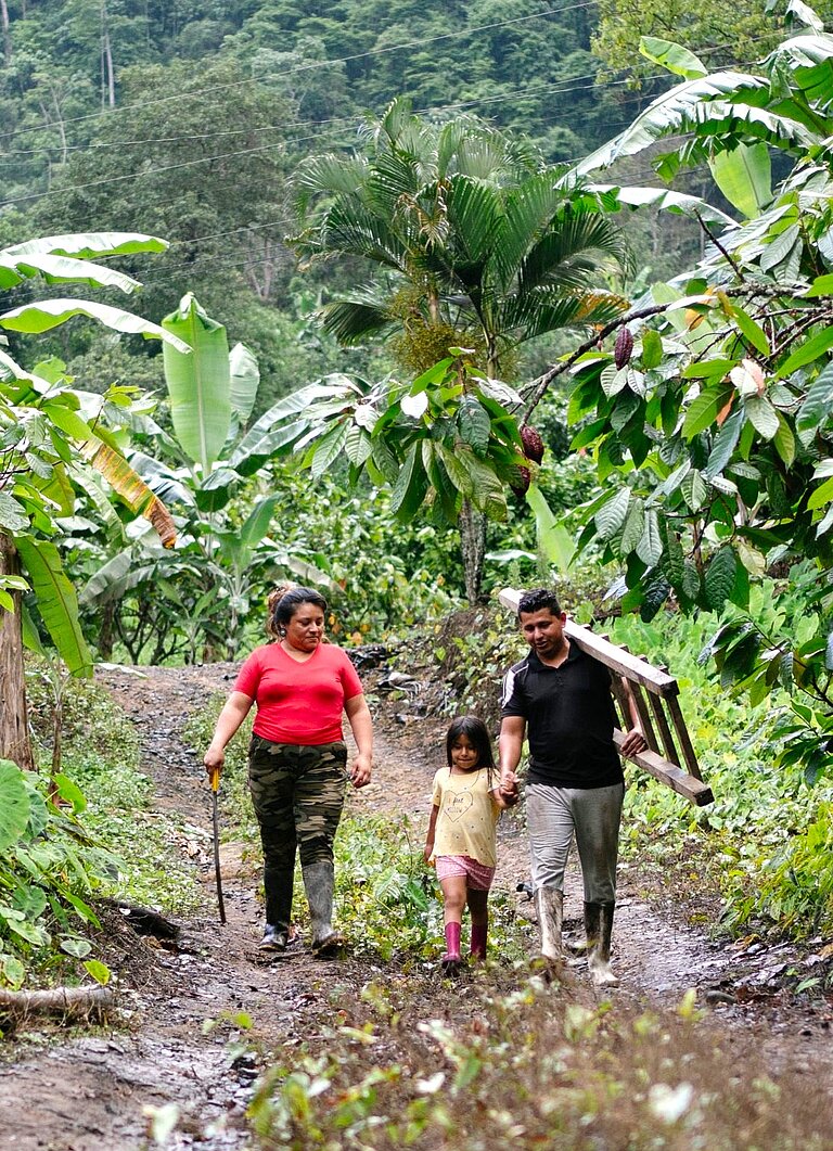 Yenny steht gemeinsam mit ihrem Mann und ihrer jüngsten Tochter in einer ländlichen Gemeinde in Ecuador.