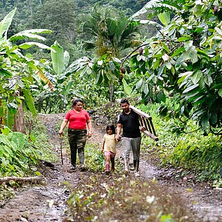 Yenny steht gemeinsam mit ihrem Mann und ihrer jüngsten Tochter in einer ländlichen Gemeinde in Ecuador.