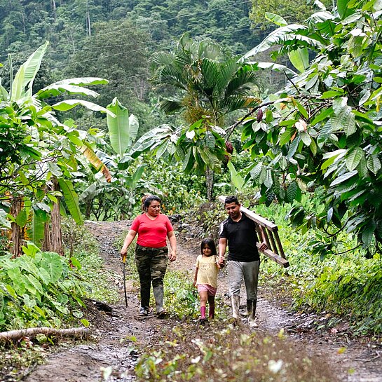 Yenny steht gemeinsam mit ihrem Mann und ihrer jüngsten Tochter in einer ländlichen Gemeinde in Ecuador.