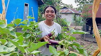 Anita erntet Auberginen in ihrem Gemüsegarten 