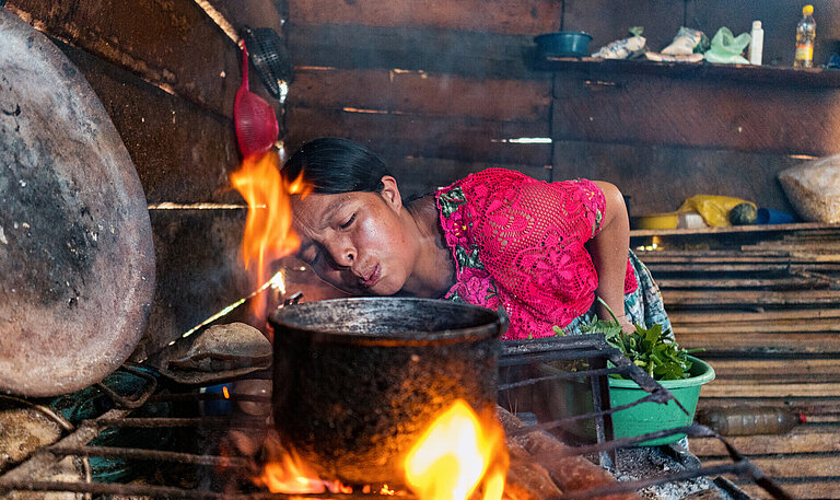 Eine Frau in Guatemala macht Feuer und kocht Essen