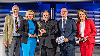 Fünf Personen stehen nebeneinander auf einer Bühne