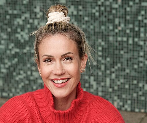 Wolke Hegenbarth Eine blonde Frau mit rotem Pullover lacht