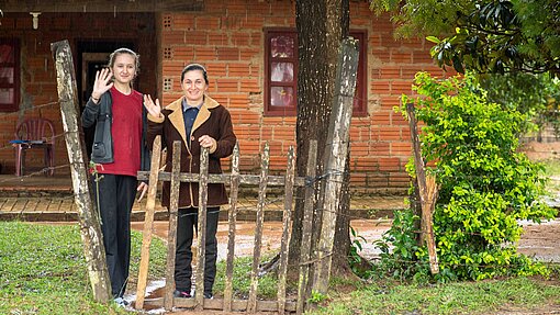 Lilian und ihre Mutter stehen vor ihrem Haus und winken.