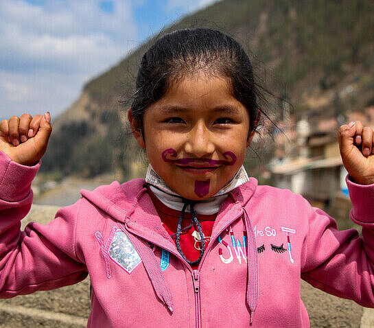 Ein junges Mädchen hat einen Bart ins Gesicht gemalt und hält zwei Fäuste in die Luft