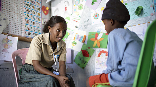 Eine Plan Mitarbeiterin leistet psychosoziale Unterstützung für Kinder.