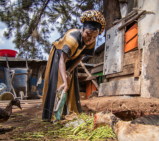 Faith fegt den Hof ihres Zuhauses in Mathare