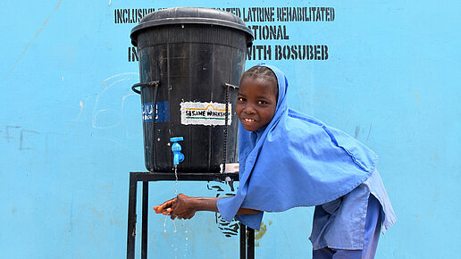 Ein Mädchen nutzt eine neue Handwaschstation von Plan International. 