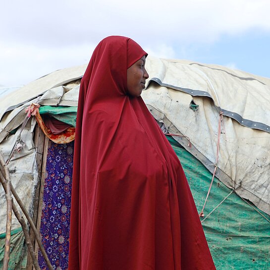 Hibo steht vor ihrem Zelt im IDP Camp