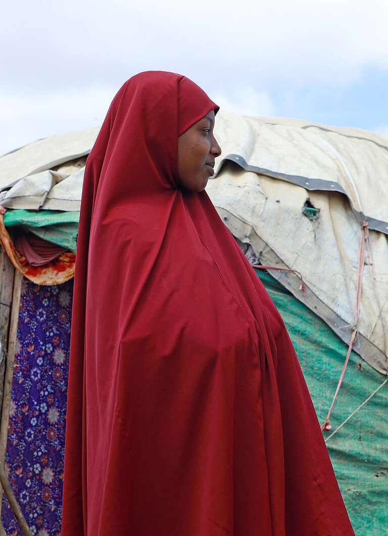 Hibo steht vor ihrem Zelt im IDP Camp