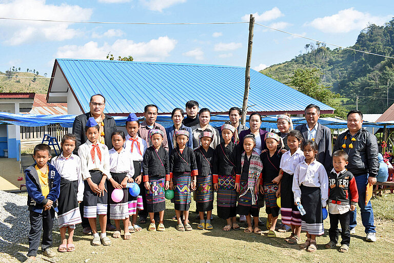 Eine Gruppe Vorschulkinder steht vor der neuen Schule in Laos