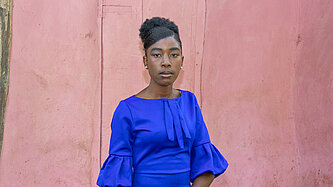 Ein junge Frau steht vor einer Hütte