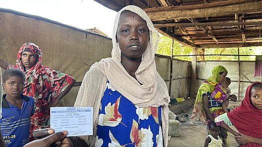 Ein Mädchen in Kurmuk, Äthiopien, erhält einen Gutschein für Essen.