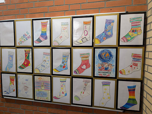 Ausstellung bunter Sockenzeichnungen von Grundschulkindern zum Klassenmotto „Coole Socken“