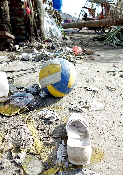 Super-Taifun Haiyan hinterließ 2013 auf den Philippinen eine Schneise der Verwüstung Eine einzelne Sandale und ein Kinderball liegen zwischen zerstörten Häusern auf der Straße