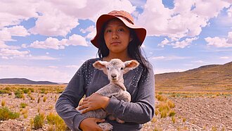 Eine Jugendliche hält ein Lamm im Arm