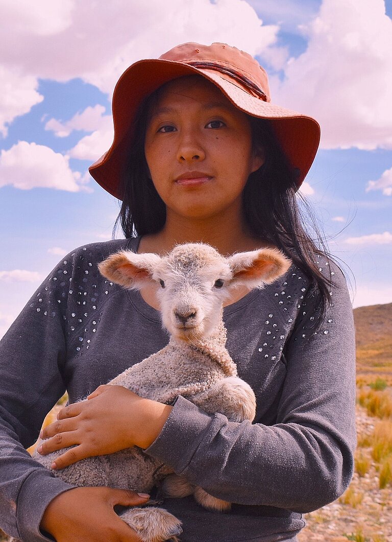 Eine Jugendliche hält ein Lamm im Arm