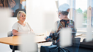 Unsere Ansprechpartnerin für Nachlässe sitzt an einem Tisch im Büro von Plan International und ist im Gespräch mit einer Unterstützerin.