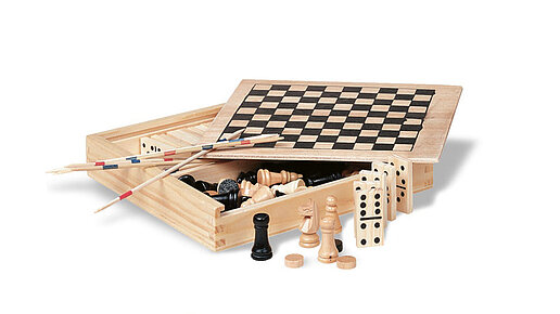 4 in 1 Spielesammlung in Holzbox Box mit geöffnetem Deckel, innen sind Spielfiguren. Davor und darauf sind Teile es Inhalts dekoriert.