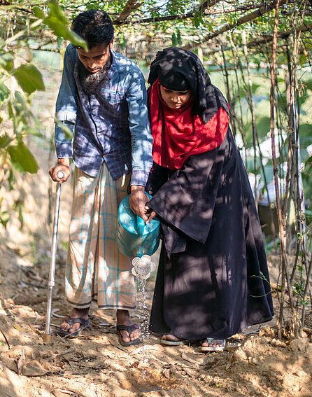 Yasmin und ihr Mann stehen zusammen in ihrem Garten in Bangladesch
