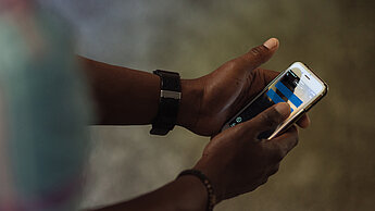 Ein Mädchen hat ein Handy in der Hand, auf dessen Bildschirm ein blaues Gleichzeichen zu sehen ist.