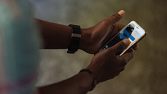 Ein Mädchen hat ein Handy in der Hand, auf dessen Bildschirm ein blaues Gleichzeichen zu sehen ist.