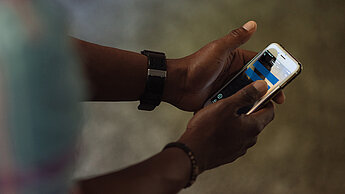 Ein Mädchen hat ein Handy in der Hand, auf dessen Bildschirm ein blaues Gleichzeichen zu sehen ist.