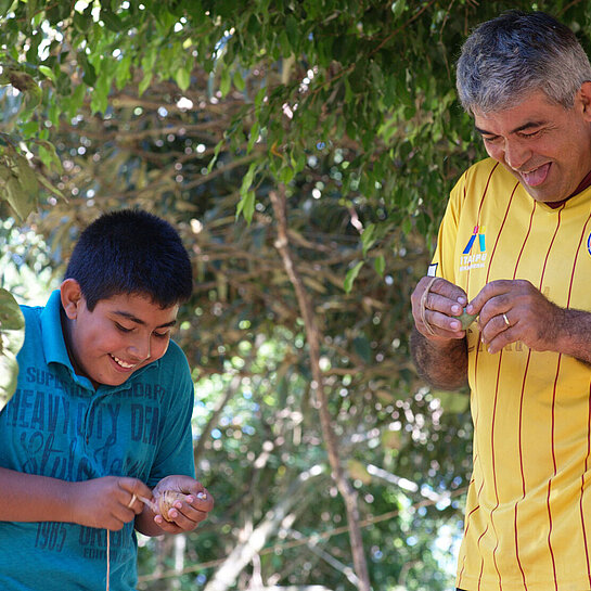 Ein Sohn und sein Vater stehen nebeneinander, halten Spielzeuge in den Händen und lachen.