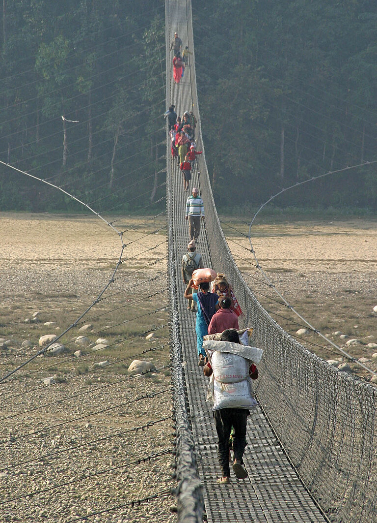 Eine typisch nepalesische Hängebrücke mit Fußgänger:innen darauf