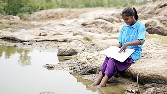 Mädchen sitzt am Wasser und lernt 