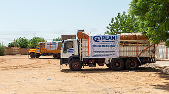 Zwei Trucks mit humanitären Hilfsgütern stehen ein einer trockenen Landschaft