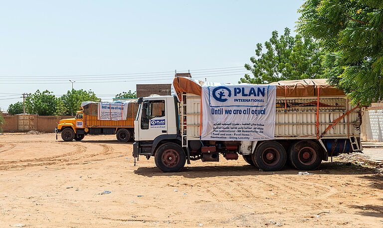 Zwei Trucks mit humanitären Hilfsgütern stehen ein einer trockenen Landschaft